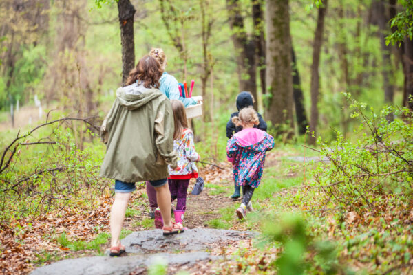 A family with three children walking on our trails in the springtime, trees and shrubs around them turning green