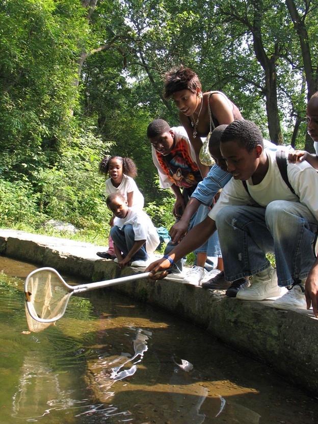 A teenager running a net through water with other children watching