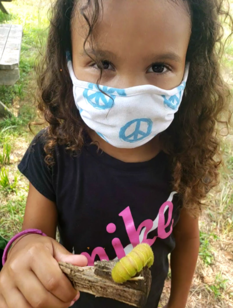 A child holding a stick with a large caterpillar on it