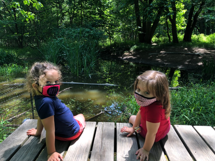 Two children sitting on a dock on a forest stream